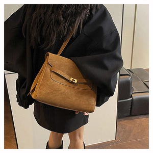 Rear view of a model wearing the brown matte leather messenger bag with gold hardware