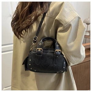 Detail of a black vintage-style crossbody bag with gold rivets and textured leather