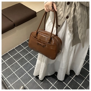 Dettaglio della borsa a spalla vintage marrone con trama in pelle lucida e fiocco