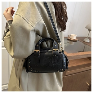 Detailed view of black retro bowling bag with golden rivet accents and shoulder strap