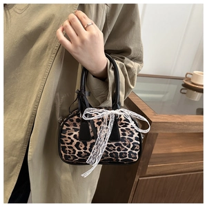 Detail of leopard print handbag featuring a white lace bow and black ribbon accents