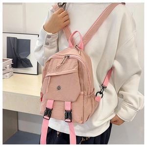 Detailed back view of pink nylon mini backpack with adjustable straps on a female model