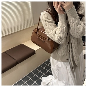 Borsa a spalla in pelle marrone con fiocco, indossata da modella in interno sobrio