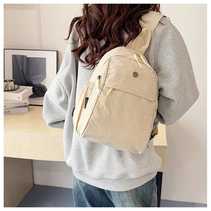 Detailed view of beige multifunctional nylon crossbody bag with zipper pockets worn by model