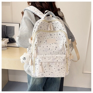 Detailed back view of a white school backpack with gray stars and a plush bear charm