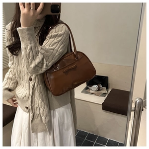 Dettaglio borsa a cuscino in pelle marrone vintage con fiocco e scritte dorate