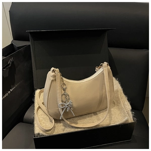Detail of cream hobo shoulder bag with sparkling rhinestone bow charm in a gift box