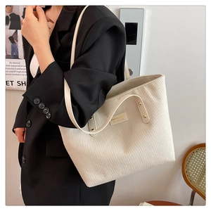 Detail of off-white corduroy tote bag showing textured fabric and fashion label