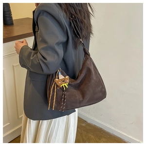 Brown large suede bucket bag with bear pendant worn by model in a minimalist style