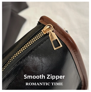 Close-up of smooth gold zipper and black glossy leather with brown trim on a handbag
