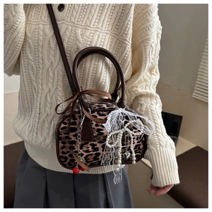 Detail of leopard print boston bag with cherry pendant on casual knit sweater outfit