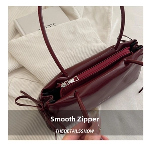 Dettaglio della cerniera argentata su una borsa sottobraccio in pelle bordeaux elegante