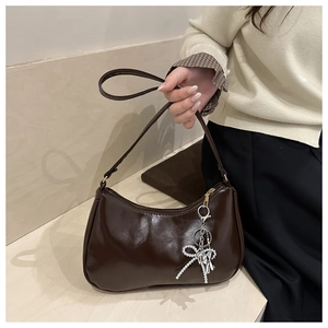 Dettaglio borsa hobo marrone scuro con ciondolo a fiocco in metallo argentato