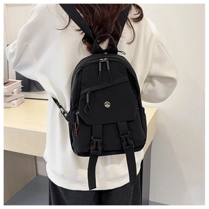Close-up of black nylon mini backpack featuring silver M logo and red zipper detail