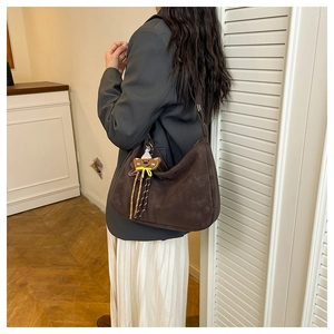 Detail of vintage brown suede hobo bag with a cute bear pendant on the shoulder