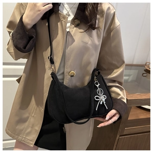 Close-up of black matte crescent shoulder bag with silver rhinestone bow pendant