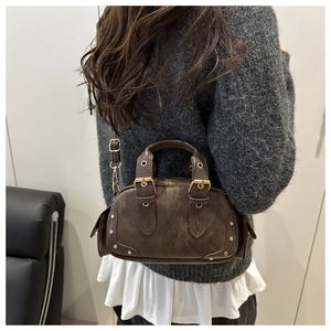 Detail view of retro dark brown leather motorcycle bag with buckles and adjustable strap