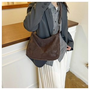 Model wearing dark brown matte leather hobo bag with sleek vertical stitching detail