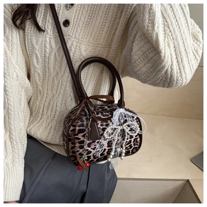 Close-up of leopard print mini Boston bag with white lace bow and cherry charm detail