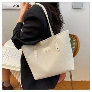 Detail of cream corduroy tote bag showing soft ribbed texture and golden metal rivets