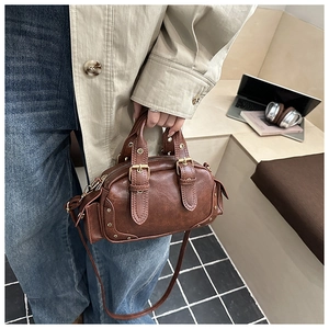Detailed view of dark brown vintage Boston bag with distressed PU leather and buckle straps