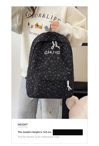Handgehaltener schwarzer Cord-Rucksack mit Herzmuster an einem 165 cm großen Model