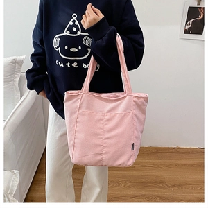 Détail d'un sac cabas en velours côtelé rose avec poches avant et texture fine