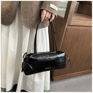 Détail du sac baguette noir brillant avec nœuds coulissants et longue poignée