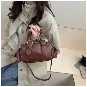 Detail of vintage dark brown faux leather bag with metallic rivets and buckle accents
