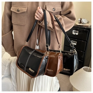 Close-up of retro glossy PU leather shoulder bags with gold hardware and logo detail