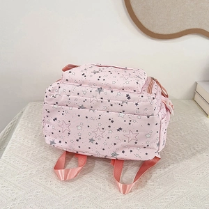 Pink school backpack for girls with star pattern on a white table in minimalist setting