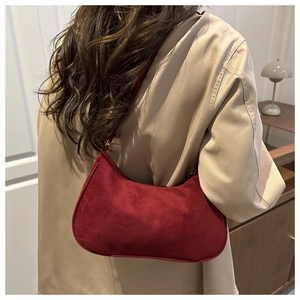 Vista dettagliata di una borsa a mezzaluna in camoscio rosso indossata con un trench