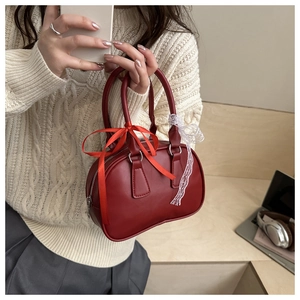 Detail of red Boston handbag featuring chic satin bows and white lace decorative accents