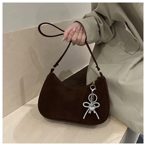 Detail of dark brown matte crescent bag with silver bow and heart charm accents