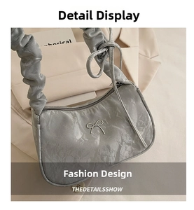 Detail der silbernen Falten-Schultertasche mit Metallschleife und gerafftem Griff