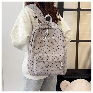 Detail eines grauen Cord-Rucksacks mit Schleifen-Print zeigt Material und Rückansicht