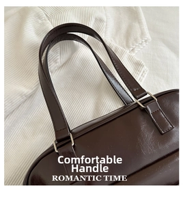 Detail of oil wax leather handle and silver metal ring on a brown underarm shoulder bag