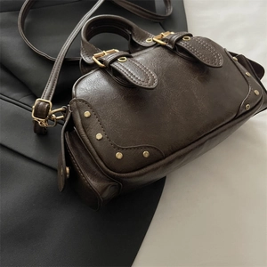 Retro dark brown boston bag with lychee texture and gold studs on a dual-tone background