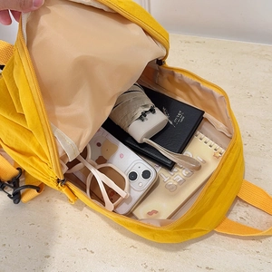 Bright yellow waterproof backpack showing spacious interior with daily essentials inside