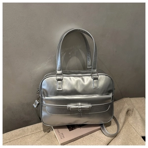 Detail of silver metallic Boston bag featuring a bow and heart pendant on fabric