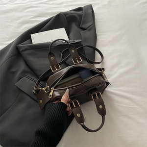 Retro dark brown doctor bag with lychee texture and gold accents on grey blazer