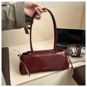 Détail du sac à bandoulière en cuir bordeaux avec texte blanc et fines bretelles doubles