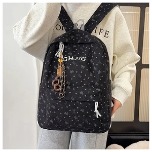 Detailansicht eines schwarzen Cord-Rucksacks mit Schleifenmuster und Deko-Anhänger