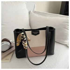 Detail of color-block tote bag on white sofa with floral scarf handle and leather logo