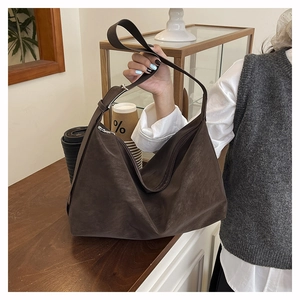 Detail of a large vintage brown suede tote bag carried in a cozy cafe setting
