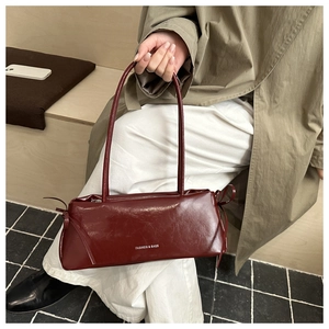 Détail du sac à bandoulière en cuir verni bordeaux avec rubans et logo de mode imprimé