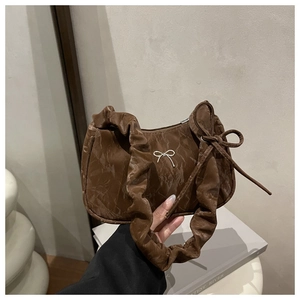Detailed close-up of dark brown pleated hobo bag with silver bow accent and knot detail