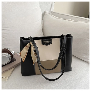 Detail of tricolor leather tote bag featuring a decorative silk scarf on the handle strap