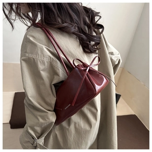 Détail du sac sous le bras bordeaux avec cordon à nœud et texture en cuir synthétique