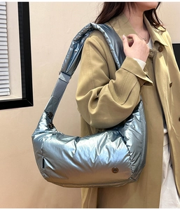 Dettaglio della borsa a tracolla imbottita blu argento metallizzato indossata dal modello